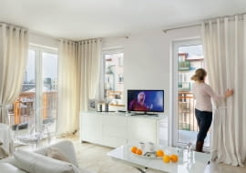 <B>W oszczędnie urządzonych wnętrzach w nowoczesnym stylu często panuje chłodna, bezosobowa atmosfera. Jest na to rada: zasłony. One ocieplą klimat wnętrza.</B> </BR> <p> </p> Okno i dwoje drzwi balkonowych (każde innej wielkości) wywoływały we wnętrzu wrażenie chaosu. Ich odmienne proporcje zniwelowano, symetrycznie upinając identyczne zasłony. Poza tym taka ilość miękkich tkanin ociepliła wystrój oszczędnie zaaranżowanego salonu, na czym tak bardzo zależało właścicielce.