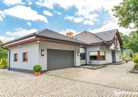 Grafitowa brama garażowa - taki sam kolor ma cokół i pas na tynku łącznika między domem a garażem