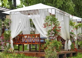 Zadaszony ogrodowy pawilon wsparty na metalowej konstrukcji daje cień ogrodowym biesiadnikom