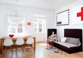 MIESZKANIE. W albumie o starym Żoliborzu jest zdjęcie domu, w którym mieszkają nasi gospodarze. Na fotografii zrobionej pod koniec lat dwudziestych ubiegłego wieku widać trzypiętrowy budynek, dookoła którego rozpościera się szczere pole. Dzisiaj to ciasno zabudowana część miasta, kilka kroków od placu Wilsona. Kiedyś peryferie, dzisiaj dobry adres. A pod tym adresem - pieczołowicie odnowione stare wnętrze. <BR /> Wspólną pasją gospodarzy jest sztuka nowoczesna. Obrazy, grafiki, plakaty i meble (ikony designu) są tutaj wszędzie. Krzesła to klasyczne modele Charlesa i Raya Eamesów z 1950 r. Obrazy nad sofą namalowala Anna Fryer, malarka obecnie mieszkająca w Tokio. Dębowy stół według projektu pani domu zrobił stolarz z Mazur. Modułowa sofa zmienia układ zależnie od potrzeb.