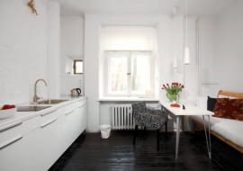 Kuchnia w wariancie 1. Na podłodze - pomalowane na czarno deski, na ścianie przy kuchennych szafkach - cegły pokryte białą farbą. Właścicielce zależało, by zachować jak najwięcej oryginalnych elementów wnętrza. Zmieniła więc tylko nieco ich wygląd.