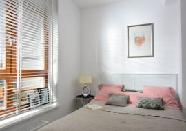 W oknie sypialni, tak jak w części dziennej, zamontowano białą żaluzję. W spokojnej aranżacji wnętrza przeważają odcienie beżu i jasnej czerwieni.