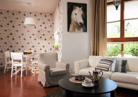 Przestronne wnętrze z efektownym wykuszem, a za oknami - morze zieleni. Wbrew pozorom to nie dom, tylko mieszkanie w podwarszawskim Konstancinie. Gospodarzy zachwycił jednak nie tylko piękny widok. Bardzo ucieszyła ich możliwość zainstalowania wymarzonego kominka. <BR /> MIESZKANIE. Kącik jadalny został zaaranżowany w sporej wnęce. Jego odrębność dodatkowo podkreślają ściany pokryte tapetą w kwiatowy wzór. W całej części dziennej uwagę zwraca podłoga - ułożone skosem deski z barwionego dębu. Do ich odcienia dobrano kolor drzwi, okiennych ram, a nawet kuchennego blatu z klejonego drewna dębowego.