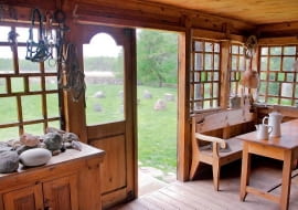 <B>Drewniany dom nad Czarną Hańczą stoi w miejscu, gdzie w epoce kamiennej była osada łowców reniferów, a potem - Jaćwingów. Prawie dwadzieścia lat temu w tej typowej chacie podlaskiej - niemal stuletniej, starannie odbudowanej po pożarze - zamieszkał nasz gospodarz. Trzeba przyznać: siedlisko w sam raz dla artysty. </B> <BR />Widok z ganku. Krąg z kamieni polnych (wśród nich znajduje się też wielki kamień młyński) został ułożony na pamiątkę Jaćwingów - ludu bałtyckiego zamieszkującego niegdyś Podlasie.