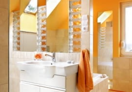 <b> Styl nowoczesny to określenie bardzo pojemne. Wystarczy spojrzeć na prezentowane przez nas trzy łazienki. Wszystkie - mimo że tak różne - hołdują nowym trendom. </b> <BR /> ORANŻOWY ŻAR. Łazienka jest duża, ale jej powierzchnia użytkowa została mocno okrojona przez skosy. Mimo to projektantce bez trudu udało się podzielić wnętrze na wyraźne strefy - przy wannie ustawiono ściankę, a po jej drugiej stronie zainstalowano umywalki. Glazura położona na części ścian i na podłodze ma neutralny odcień. O wyrazistości wnętrza zadecydował odważny pomarańczowy odcień farby, którą pokryto skosy oraz sufit. Lustra zostały obramowane luks- ferami. Zdaniem projektantki to idealny materiał konstrukcyjny, który jednocześnie nie zabiera światła ani przestrzeni. Przy wannie znajduje się zsyp na brudną bieliznę, prowadzący bezpośrednio do pralni na parterze.