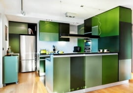 PRZECHOWYWANIE W KUCHNI. Aneks kuchenny i pokój dzienny są dobrze oświetlone zarówno światłem naturalnym, jak i sztucznym, nie trzeba więc było dodatkowo rozjaśniać wnętrza jasnymi meblami. Gospodarze zdecydowali się na ciemniejsze i jaśniejsze odcienie zieleni, które stworzyły przyciągającą wzrok mozaikę. Ściana nad blatem roboczym jest nieco chropowata - pokryto ją tynkiem strukturalnym imitującym beton.