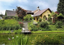 Blick ´ber den Teich auf das Haupthaus mit der Treppe runter zu dem Steg mit Gartenstuhl, am Hang Rosen (Rosa) im Garten Feistritz. SLOWA KLUCZOWE: Bach Badeteich Blumentopf Blument^pfe Camellia Feistritz Garten Gartenhaus Gartenm^bel Gartenreportage Gartenstuhl Gartentisch gelb Hanggrundst´ck Hanggrundst´ck Haus Holland h^lzern aus Holz Holzstuhl Juni Kamelie ÷sterreich ÷sterreich Rasen Reportage rosa Steg Stuhl Teich Tisch Treppe Ufer Wiese Ferdinand Graf Luckner FocusOnGarden Feature Gartenfeature Querformat