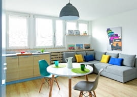 Po połączeniu kuchni z pokojem powstała spora strefa dzienna. Z jej nowoczesnym wystrojem harmonizują dekoracyjne dodatki nawiązujące do lat 60., kiedy wybudowano mieszkanie. Nadrukowane na blachach i na płótnie plakaty reklamujące osiągnięcia PRL-owskiej motoryzacji zostały kupione w sklepie Reset, który specjalizuje się w stylu vintage.