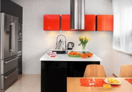 Można w niej umieścić sprzęt AGD, pojemne szafki i szuflady, może też służyć jako miejsce do jedzenia albo do pracy. Odkąd wyspa pojawiła się w naszych kuchniach, pełni coraz więcej funkcji i coraz lepiej wygląda. <BR /> KUCHENNA WYSPA. Wyspa, a właściwie półwysep, gdyż mebel stoi przy ścianie, jest prawdziwym centrum dowodzenia. Tutaj bowiem wykonuje się najważniejsze kuchenne czynności: przygotowanie produktów, gotowanie i zmywanie. W szerokim półwyspie zainstalowano zlewozmywak, a naprzeciwko niego - płytę elektryczną. Mimo początkowych obaw pani domu takie usytuowanie tych urządzeń sprawdza się w codziennym życiu. Jest też spory blat roboczy i pojemne schowki. Punkty świetlne w okapie i pod szafkami wiszącymi zapewniają wystarczająco dobre warunki do pracy. W dzień na blat pada naturalne światło z okna. Szeroki półwysep zajmuje centrum strefy kuchennej. Tę część wnętrza optycznie wyznacza podwieszony sufit (z halogenami i listwami LED) oraz podłoga z polerowanego gresu. Ścianę wyłożono okładziną o fakturze imitującej kamień.