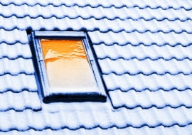 Okno dachowe. Zalegający zimą śnieg.