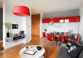 W tym wnętrzu zamieszkał student. Jednak wbrew pierwszemu skojarzeniu nie ma tu tymczasowych rozwiązań ani przypadkowych mebli. Gospodarz dostał mieszkanie w prezencie od rodziców na nowe, dorosłe życie, dlatego zostało urządzone tak, by kiedyś mogła w nim mieszkać rodzina. <BR /> MIESZKANIE. Drzwi wejściowe i ścianę wokół nich wykończono dębowym fornirem. Na podłodze - dębowy parkiet. Kąt jadalny został zaaranżowany na zasadzie łączenia kontrastów: przy czarnym stole stoją krzesła z czerwonymi oparciami. Czerwone fronty wiszącej szafki, zrobione ze szkła lacobel, wyróżniają się na tle jasnej ściany.