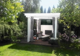 Altana ze ścianą wodną z tyłu to idealne miejsce do wypoczynku. Została ulokowana w głębi ogrodu, w sąsiedztwie kwitnących hortensji i okazałego tulipanowca.