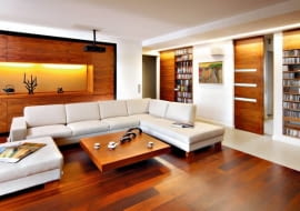 <b> ŁADNIE SCHOWANE. Szafki i regały w salonie powinny nie tylko dobrze spełniać swoją funkcję, ale i estetycznie wyglądać. A to zależy od formy mebli oraz materiału, z jakiego są zrobione. </b> <BR /> Właścicielom, kinomanom i melomanom z zamiłowania, zależało na przechowywaniu w salonie bogatych zbiorów filmów i płyt muzycznych. Potrzebowali więc pojemnych schowków, ale takich, które nie dominowałyby nad wypoczynkową funkcją pomieszczenia. Projektanci zaproponowali zbudowanie w ściennych wnękach otwartych półek na płyty CD i DVD, które prezentują się efektownie, oraz zamykanych szafek na rzeczy nie do eksponowania. Zabudowa okazała się trafionym pomysłem - nie przytłacza wnętrza tak jak masywne wolno stojące meble. Lekka forma schowków idzie w parze z urodą drewna orzechowego, z jakiego zostały zrobione. <BR /> Kredens w nowoczesnym wydaniu. Obszerną wnękę w jednej ze ścian zabudowano szafkami zamykanymi pełnymi drzwiczkami bez uchwytów. We wnęce w środku tej zabudowy gospodarze eksponują dekoracyjne drobiazgi.