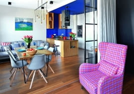 JEDNĄ ZE ŚCIAN w pokoju dziennym wyłożono... białymi płytkami gresu, których faktura przypomina malowane drewno. Na ich tle pięknie prezentuje się obraz Darii Samołyk "Jezioro z przebłyskiem". Fotel Greta i sofa Tokio pochodzą z firmy Sits, krzesła Lars Colour kupiono w Le Pukka. Kąt wypoczynkowy oświetla lampa Pole Six (z Kare Design) składająca się z sześciu żarówek zawieszonych na różnej wysokości.