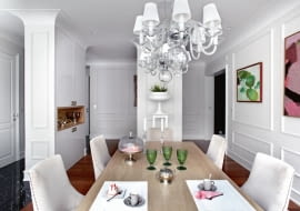 Jadalnia i kuchnia otwierają się na siebie. Stół Paola z blatem z bielonego dębu, krzesła Sophie, żyrandol Egmont, symetrycznie wiszące lampy nad stołem, w głębi na postumencie donica Deauville (BBHome).