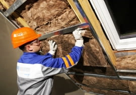 Układanie na metalowym ruszcie drugiej warstwy wełny mineralnej jako ocieplenia dachu