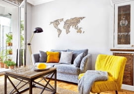 KONTURY KONTYNENTÓW na ścianie nad kanapą zostały wycięte laserem ze sklejki. Wykonawcę tej precyzyjnej roboty gospodarze znaleźli na portalu dawanda.pl; sami pomalowali natomiast sklejkę bejcą - na ten sam kolor co blat stolika kawowego.