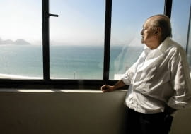 Brazilian architect Oscar Niemeyer looks at the Copacabana beach from his office after his interview with Reuters in Rio de Janeiro, in this June 16, 2003 file photo. Niemeyer, a towering patriarch of modern architecture who shaped the look of contemporary Brazil and whose inventive, curved designs left their mark on cities worldwide, died late on December 5, 2012. He was 104. Niemeyer had been battling kidney and stomach ailments in a Rio de Janeiro hospital since early November. His death was the result of a lung infection developed this week, the hospital said, little more than a week before he would have turned 105. REUTERS/Sergio Moraes/Files (BRAZIL - Tags: OBITUARY SOCIETY)