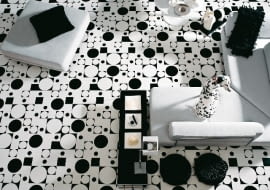 Odważna kolorystycznie wykładzina w postaci geometrycznej układanki stanowi tło dla wnętrza konsekwentnie zaprojektowanego w barwach bieli i czerni.