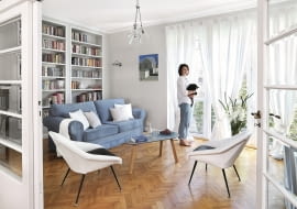 Salon z oknami wychodzącymi na południe to najwidniejszy pokój w mieszkaniu. Biblioteczka została zrobiona na zamówienie. Witrynkę (w rogu za drzwiami) gospodyni zestawiła z prostą welurową kanapą ze sklepu Livingroom, stolikiem vintage (Nap) i fotelikami z lat 60., na których uwielbia wylegiwać się kotka Hesia.