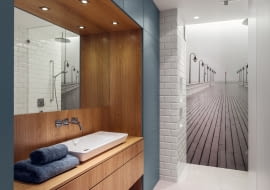 W łazience uwagę przykuwa czarno-białe zdjęcie orłowskiego molo, a także wnęka w wykończeniu z dębowej czeczoty, która pięknie kontrastuje z morską barwą meblowej zabudowy. To w niej chowają się kosmetyki, pralka, deska do prasowania i pozostałe przybory potrzebne do utrzymania porządku. Dzięki temu łazienka jest uporządkowana.