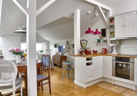 Słupy wyznaczają granicę między aneksem kuchennym a pokojem dziennym. Projektując kuchnię, pani domu zrobiła najpierw spis niezbędnych naczyń i akcesoriów, a następnie policzyła, ile potrzeba szuflad, by je wszystkie pomieścić. Gotowe sosnowe szafki z IKEA pomalowała na biało.