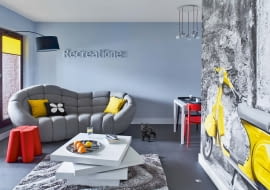 SALONIK, CZYLI ODPOCZYNEK. Włoskie słowa i przysłowia są rozsiane na ścianach w całym mieszkaniu, podkreślając przeznaczenie różnych miejsc. To pierwszy dowód na miłość Julity do Włoch. Drugi to skuter Vespa na fototapecie (prawdziwy stoi w garażu). Poduszki są ze sklepów Nap i Scandinavian Living, filcowy stołek i figurka buldoga - z Noti.