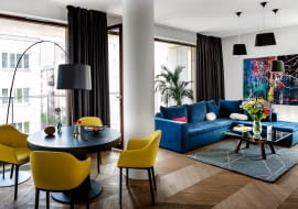 Dębowy parkiet ułożony w paryską jodełkę (komosinski.eu) nadaje wnętrzu modny, ale i ponadczasowy charakter. Obraz "Abstrakcja 5" Łukasza Stokowskiego (Galeria Ornament). Stolik ze szklanym blatem (Fritz Hansen), dywan (Hay Dot), filcowe lampy sufitowe Felt Shade Toma Dixona.