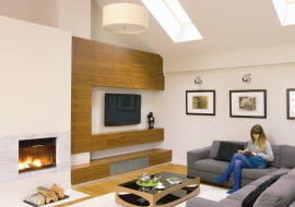 Przestrzeń oraz wysokość to dwa największe architektoniczne atuty domu Moniki i Piotra. Projektantka umiejętnie podkreśliła je minimalistycznym wystrojem, bez nadmiaru mebli i ozdób. <BR /> DOM. Kąt wypoczynkowy w salonie urządzono pod oknami połaciowymi. Przy kominku o geometrycznej obudowie wykończonej marmurem powstała nowoczesna zabudowa z szafkami, fornirowana drewnem orzecha amerykańskiego. Dębowe belki stropowe pasują do prostego wystroju wnętrza.