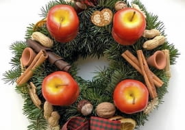 Ozdoby adwentowe. Wieniec ze świecami-jabłkami, laskami cynamonu, orzechami i drobnymi dekoracjami ceramicznymi