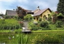 Blick ´ber den Teich auf das Haupthaus mit der Treppe runter zu dem Steg mit Gartenstuhl, am Hang Rosen (Rosa) im Garten Feistritz. SLOWA KLUCZOWE: Bach Badeteich Blumentopf Blument^pfe Camellia Feistritz Garten Gartenhaus Gartenm^bel Gartenreportage Gartenstuhl Gartentisch gelb Hanggrundst´ck Hanggrundst´ck Haus Holland h^lzern aus Holz Holzstuhl Juni Kamelie ÷sterreich ÷sterreich Rasen Reportage rosa Steg Stuhl Teich Tisch Treppe Ufer Wiese Ferdinand Graf Luckner FocusOnGarden Feature Gartenfeature Querformat