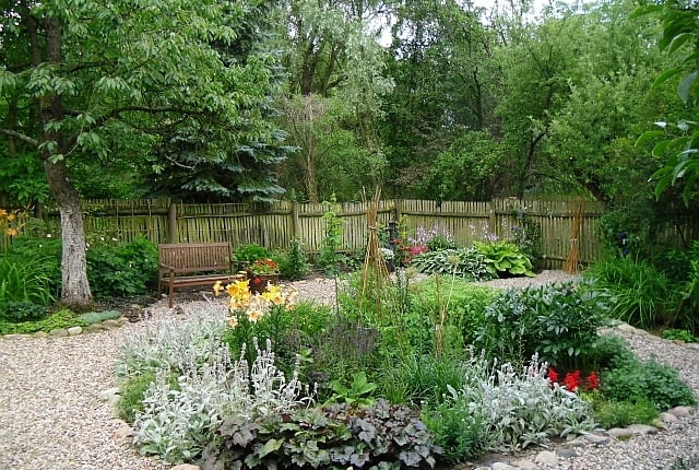 W wilgotnym, lekko zacienionym miejscu rosną funkie, tawułki i języczki. Z ceramicznej beczki pod nieczynną pompą 'wypływają' smagliczki