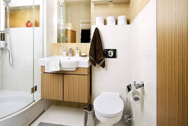 NA STRAŻY PORZĄDKU. Pomieszczenie jest dość małe, dlatego projektantki od razu zaproponowały, by zainstalować w nim kabinę prysznicową zamiast wanny (mniejszy jej model w ogóle nie wchodził w grę, bo obydwoje właściciele są wysocy). Dzięki temu udało się zaoszczędzić sporo miejsca, które można było przeznaczyć na meble służące do przechowywania zapasów środków czystości i innych akcesoriów. I tak znalazły się tu dwie wolno stojące szafy oraz szafka pod umywalkę. Płytki ceramiczne, którymi wyłożono wnęki i fragmenty ścian, zostały idealnie dopasowane do wzoru okleiny na łazienkowych meblach - mają tylko jaśniejszy odcień niż ona (projekt wnętrza: Weronika Steffen-Lotarska, Olga Werikowska).