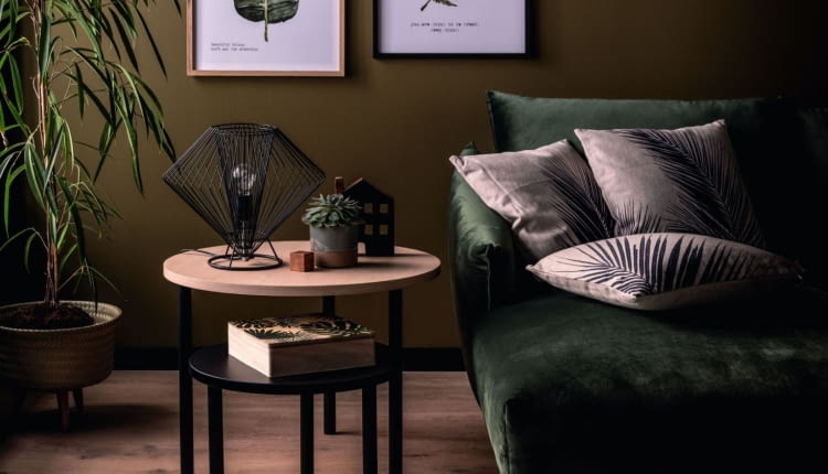 Botaniczne motywy na plakatach, zieleń ściany i sofy, drewniana podłoga oraz żywe rośliny – to wszystko tworzy we wnętrzu niepowtarzalny klimat, przypominający leśny zakątek. Galeria Wnętrz Domar/Meble Vox