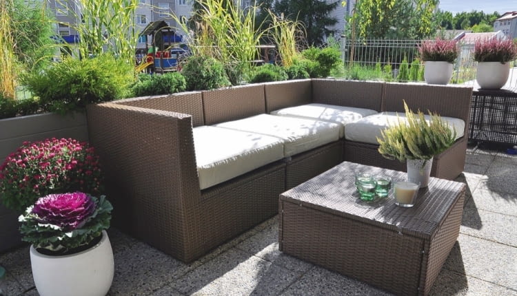 WZDŁUŻ AŻUROWEJ BARIERKI tarasu rosną iglaki w donicach i trawy ozdobne posadzone w skrzyniach.