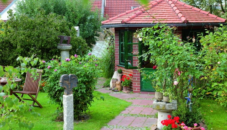 Gepflasterter Weg zum Gartenhaus, Rosa ( Rosen ), Pelargonium ( Geranien ) in Tpfen, Sitzplatz auf dem Rasen, getpferte KunstobjekteBezug : www.ton-art-jmp.de Tel.: 08752-168761039806, 61039807