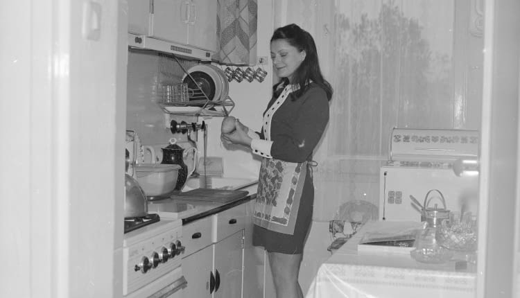 Danuta Krotowicz obiera gruszkę w kuchni. Widoczna kuchenka gazowa 'Warta', zlew i suszarka do naczyń.