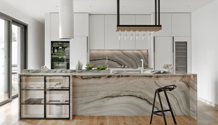 Pięknie zaprojektowana kuchnia może być prawdziwą ozdobą. Tutaj wyeksponowano wzór materiału użytego do wykończenia ściany nad blatem i boków kuchni. Białe meble są tylko tłem dla niego.