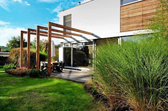 Konstrukcja pergoli podkreśla podział przestrzeni tarasu na dwie strefy: zadaszoną jadalnię i słoneczną plażę.