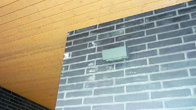 Białe wykwity na fragmencie klinkierowej elewacji pod podbitką dachową