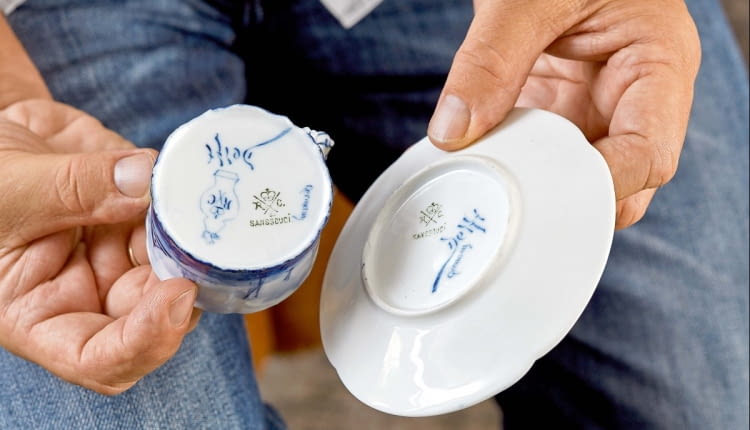 ...kiedy część wyprodukowanej porcelany wysyłano do Delft, miasta znanego z kunsztu holenderskich malarzy zdobiących słynny fajans. Na denku są więc sygnatury obydwu manufaktur.