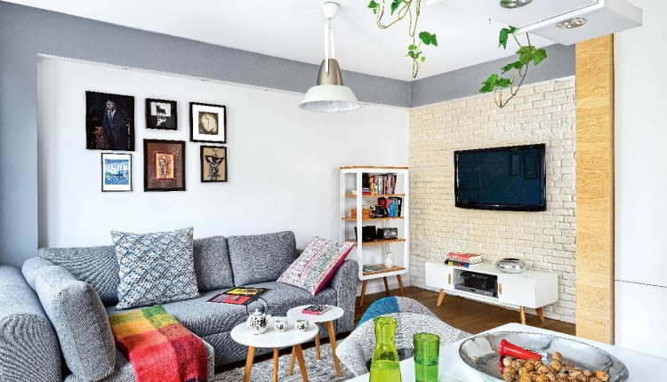 STONOWANE BARWY. W całym mieszkaniu dominują spokojne beże, biele i szarości, żywsze kolory występują tylko w dodatkach. W ścianie, na której wisi dziś telewizor, była niepraktyczna wnęka. Architektka zlikwidowała ją (powiększając dzięki temu garderobę), a nowo postawioną ścianę wyłożyła płytkami imitującymi cegłę (sklep Bartico). Pod sufitem zaprojektowała ramę z płyty gipsowo-kartonowej, w której zamontowano oświetlenie punktowe. Kanapa jest ze sklepu Agata, dywanik z decoretro.com.pl Obrazy na ścianie Beata przywiozła z egzotycznych podróży. Na przykład akcenty orientalne wiążą się z wyprawą do Chin, gdzie organizowała festiwal 'Polskie Kręgi Sztuki'.