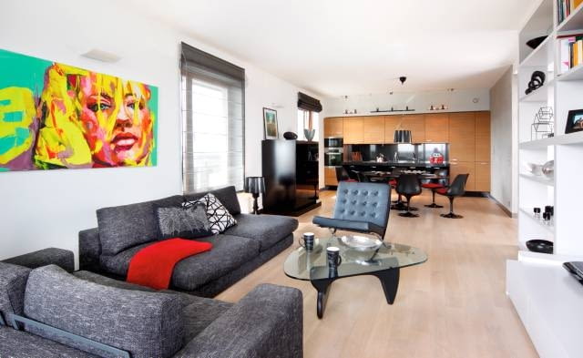 W kuchni zainstalowano listwy oświetleniowe z halogenami, nad stołem jest lampa wisząca, a w części wypoczynkowej - kinkiety i reflektorki. We wnętrzu dominują ciemne szarości i czerń rozjaśnione dużymi płaszczyznami bieli i kremowego beżu.