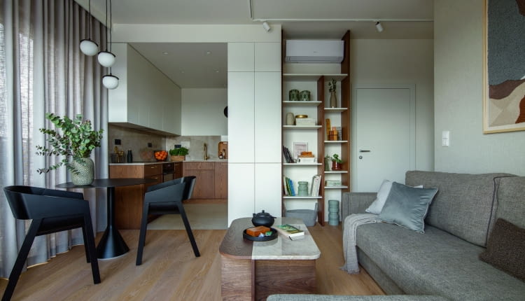 Nieduża strefa dzienna z salonem i aneksem kuchennym dzięki wysokim oknom oraz oszczędnemu wyposażeniu zyskuje poczucie przestrzeni. Wnętrze prezentuje się swobodnie i nie jest przytłoczone nadmiarem mebli czy dodatków.