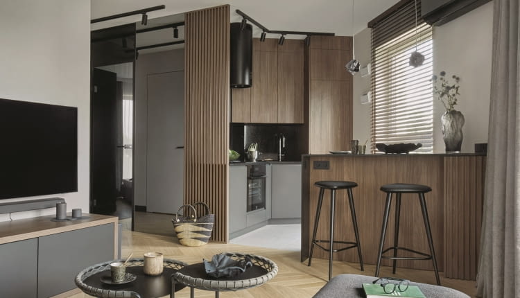 Kuchnia w kolorach i materiałach powtarzających się w aranżacji salonu tworzy spójną z przestrzenią dzienną, wspólną stylistycznie strefę.