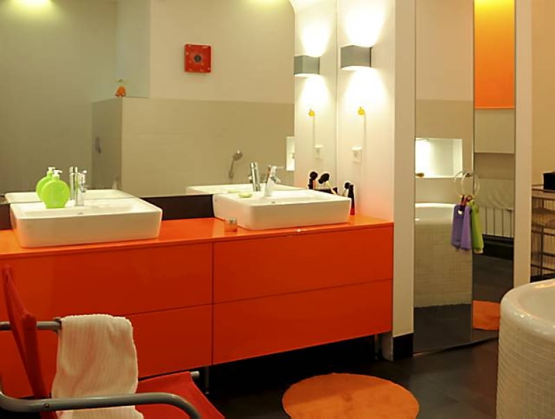 W niszy zmieściła się szeroka szafka z płyty lakierowanej na wysoki połysk. Jej wyrazista barwa jest najmocniejszym akcentem kolorystycznym we wnętrzu. Obok znajduje się szafa wnękowa zamykana lustrzanymi drzwiami.