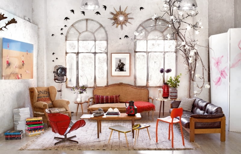 Ludwikowska sofa tapicerowana lnem, stary fotel obity jutowym workiem, reinterpretacja słynnego obrotowego krzesła Swan Arne Jacobsena, wykonana z beczek po benzynie przez firmę PO!Paris. Między oknami zdjęcie malijskiego fotografa Seydou Keity. dom