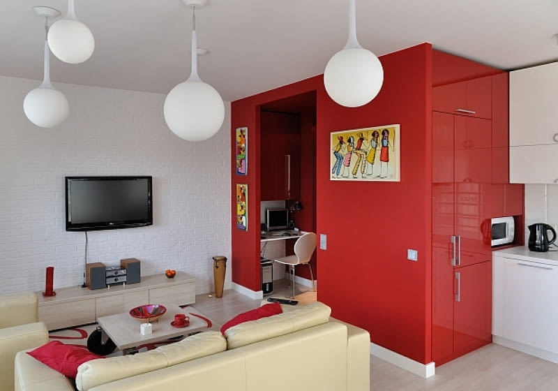 W centralnej części mieszkania architekci postawili czerwony kubik. Od strony kuchni mieszczą się w nim szafki kuchenne i lodówka, a od strony korytarza - szafy, pralka oraz małe biuro. nowoczesne mieszkanie, jak urządzić mieszkanie, mieszkanie w stylu loft, miniloft