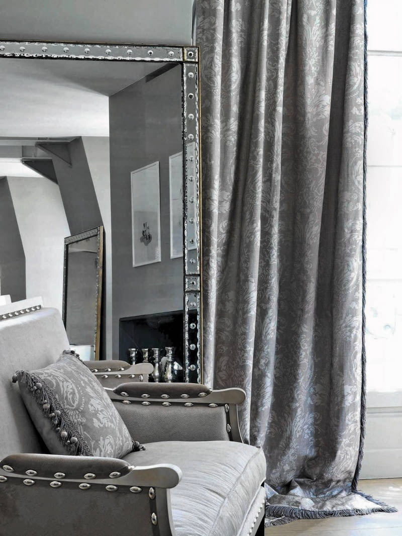 Zasłonę oraz poduszkę wykonano z tkaniny Eos. Bogaty barokowy wzór jest tylko o ton jaśniejszy od tła, dlatego wydaje się bardzo subtelny. Tak zaprojektowany materiał, mimo historycznego pochodzenia,świetnie sprawdzi się we wnętrzach współczesnych. Dostępny w pięciu wersjach kolorystycznych, Houles.