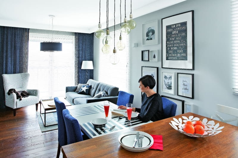 SPORY STÓŁ (ze sklepu Take me Home) z tapicerowanymi krzesłami (domartstyl.eu) przystawiono do wyspy. Ewa i Marek bardzo sobie chwalą to rozwiązanie, bo przygotowując posiłek dla gości, nie czują się wyłączeni z życia towarzyskiego. Ozdobą tej części pomieszczenia jest galeria grafik, zdjęć i plakatów oprawionych w białe i czarne ramki. Nad stołem - siedem lamp-żarówek (bylight.pl).